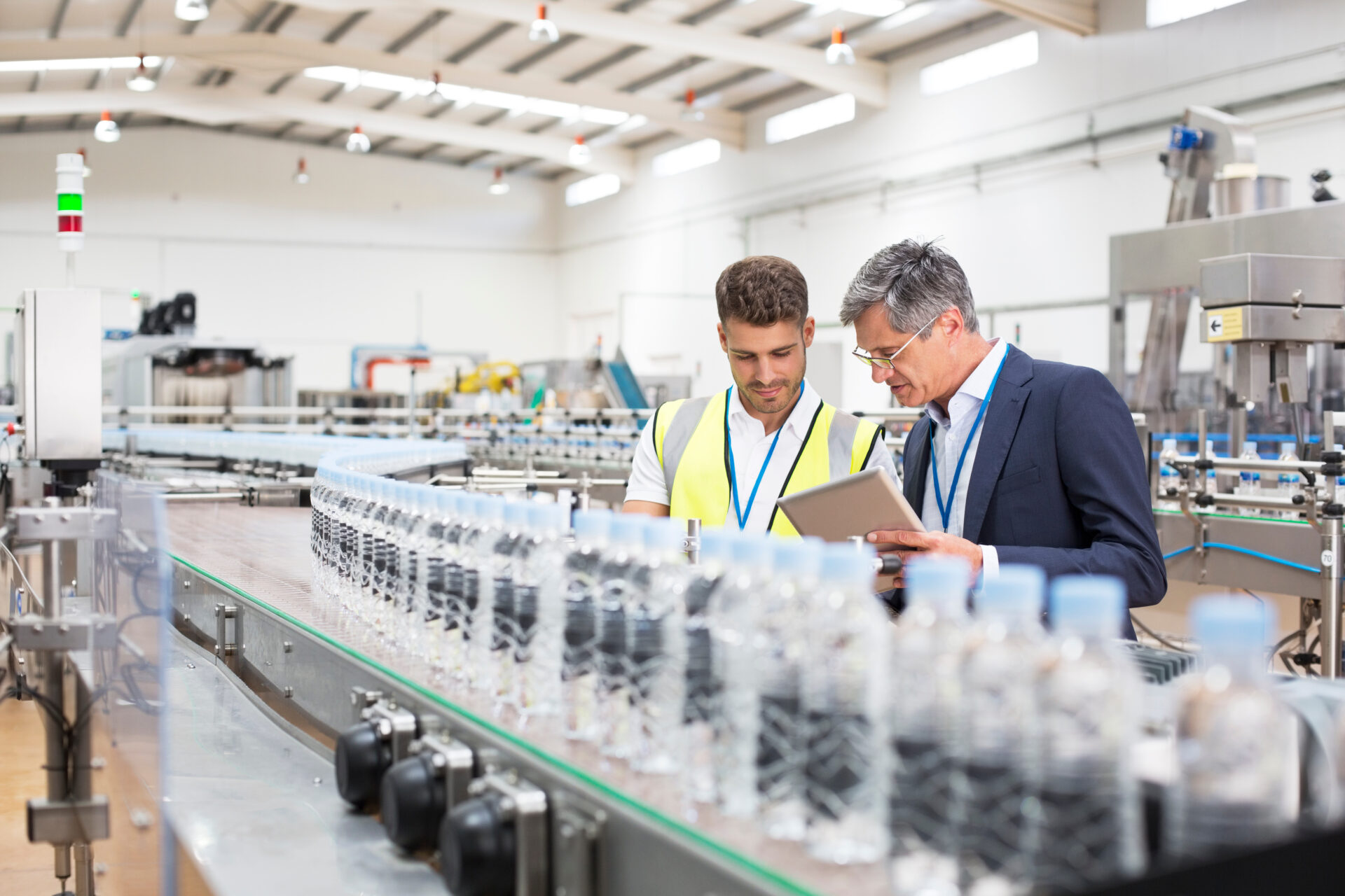 Supervisor and manager watching plastic bottles on conveyor belt